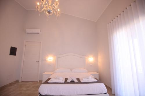 a white bedroom with a bed and a chandelier at B&B Royal in Sellia Marina
