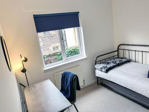 1 dormitorio con cama, ventana y mesa en Castlegate en Lanark