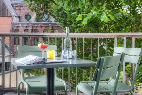 a table with chairs and a glass of wine on a balcony at Hotel Arena in Amsterdam