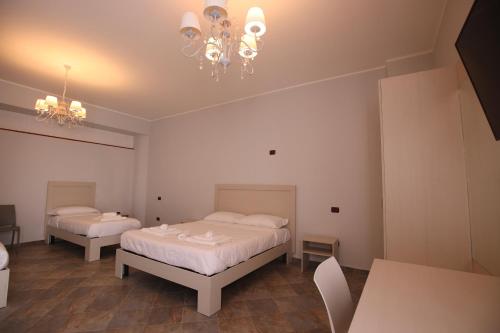 a bedroom with two beds and a chandelier at B&B Royal in Sellia Marina