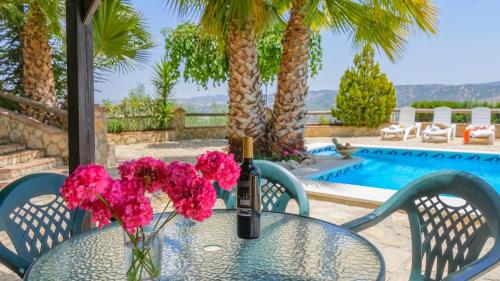 a glass table with a bottle of wine and pink flowers at Combinación Cortijo y Mirador Casablanca Priego de Córdoba by Ruralidays in Priego de Córdoba