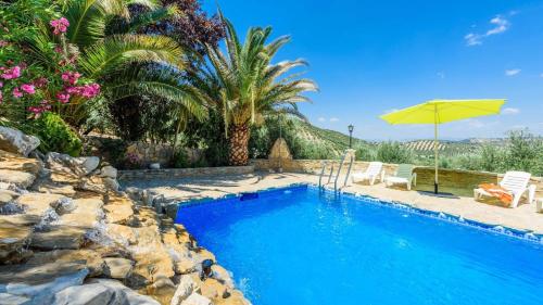 a pool with a umbrella and chairs and a palm tree at Combinación Cortijo y Mirador Casablanca Priego de Córdoba by Ruralidays in Priego de Córdoba