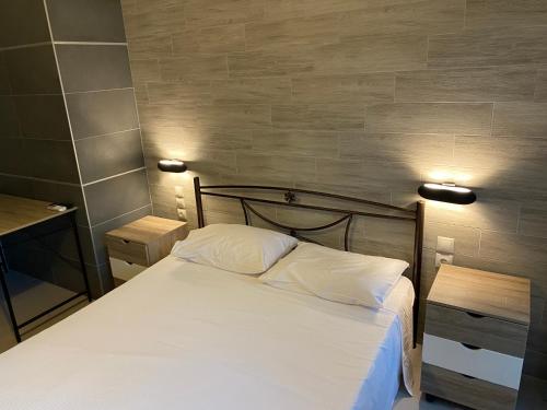 a bedroom with a bed with white sheets and two lamps at Luxury suite felicia with fireplace by the lake in Pérama