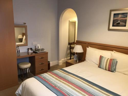 1 dormitorio con cama, escritorio y espejo en The Bowden Lodge en Southport