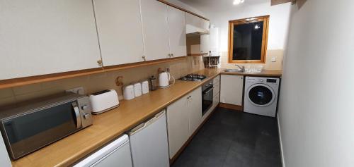 a kitchen with white cabinets and a washer and dryer at Spacious, modern 3 bedroom luxury flat in centre location in Broughty Ferry