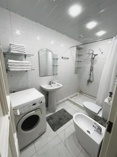 a white bathroom with a sink and a washing machine at Апартаменты с тремя спальнями in Yerevan