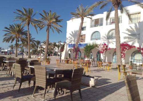 a patio with tables and chairs and palm trees at Djerba house in Houmt Souk
