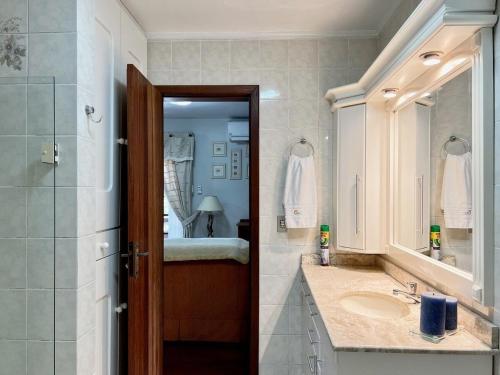 La salle de bains est pourvue d'un lavabo, d'une douche et d'un miroir. dans l'établissement Apartamento 3 DORM apenas 1 QUADRA LAGO NEGRO, à Gramado