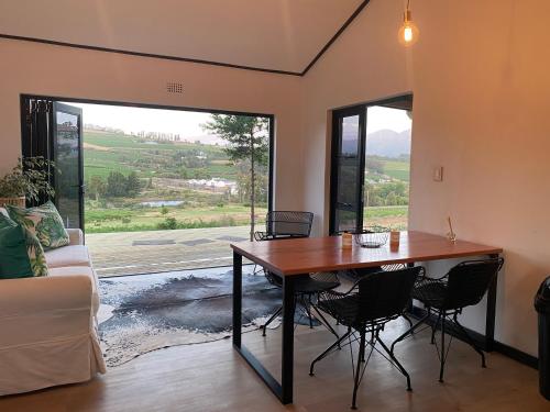 Stellenbosch的住宿－The Log Cabin Lodge，一间带桌椅和大窗户的用餐室
