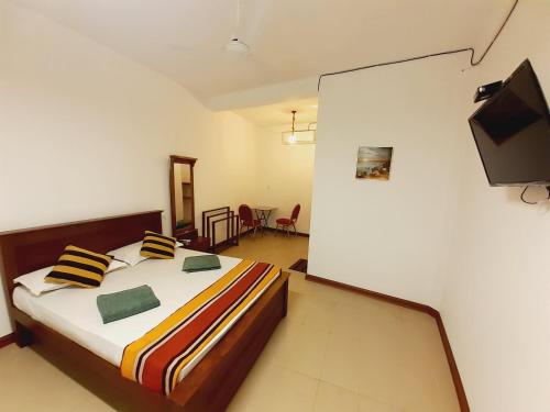 a bedroom with a bed and a flat screen tv at Royal Crown Residence in Talawatugoda