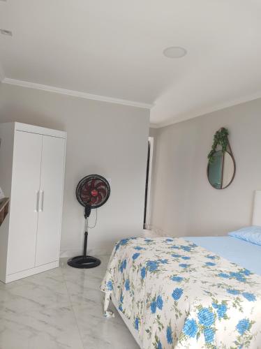 a white bedroom with a bed and a fan at Loft Belas Praias in Arraial do Cabo