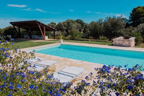 - une piscine avec 2 chaises et un pavillon dans l'établissement Trulli Paparale, à Alberobello