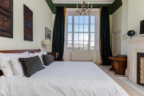 a bedroom with a large white bed and a fireplace at 21 Montpellier House - By Luxury Apartments in Cheltenham