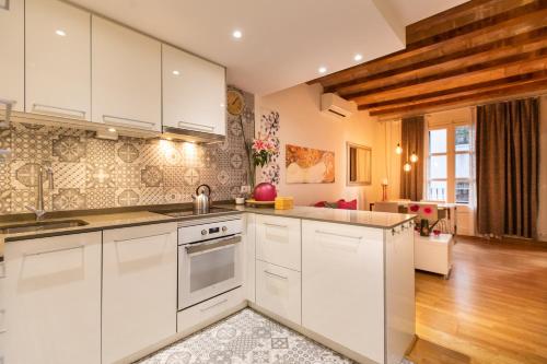 cocina con armarios blancos y sala de estar. en Blasco de Garay Apartment - Poble Sec, en Barcelona