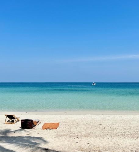 a chair and a bag on a beach with the ocean at Pen's Bungalow Koh Phangan in Thong Nai Pan Yai