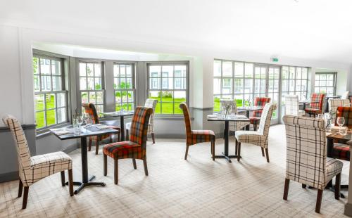 un restaurante con mesas, sillas y ventanas en Green Hotel en Kinross