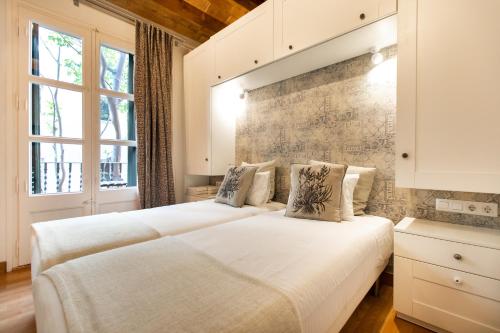 two beds in a room with two windows at Blasco de Garay Apartment - Poble Sec in Barcelona