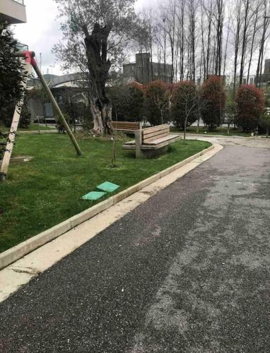 an empty street with a park with a bench on the grass at Spacious apartment in luxury residence in Çeliku