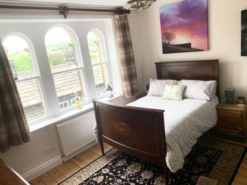 a bedroom with a bed and two windows at Artist Hideaway Main Street Haworth in Haworth