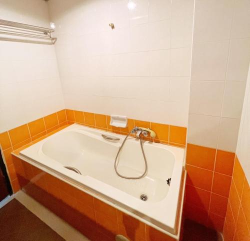 a bath tub in a bathroom with orange and white tiles at THE POPULAR PLACE in Ban Khlong Thewa