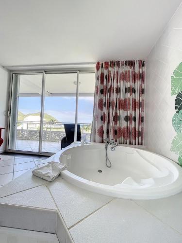 a large white bath tub in a room with windows at Le Domaine Anse Marcel Beach Resort in Anse Marcel 