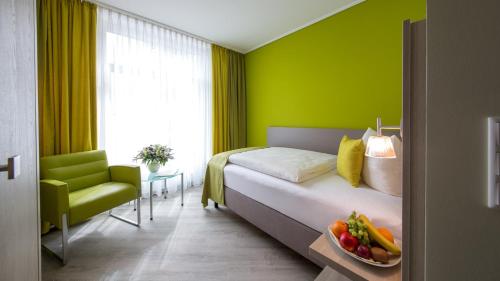 ノルダーナイにあるMichels Inselhotel Vier Jahreszeitenの緑の壁のベッドルーム1室、ベッド1台(フルーツボウル付)