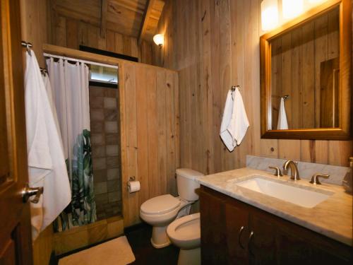 drewniana łazienka z toaletą i umywalką w obiekcie Hummingbird Beach House w mieście West Bay
