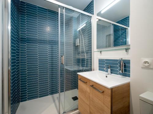 La salle de bains est pourvue d'un lavabo et d'une douche avec du carrelage bleu. dans l'établissement Le Lion - Plain-pied, WIFI, YT Premium - 2RFHomes, à Château-Thierry