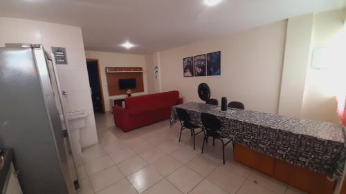 um quarto com uma mesa e cadeiras e um sofá vermelho em Apartamento Temporada em Cabo Frio Arraial do Cabo Cantim do Goiano em Cabo Frio