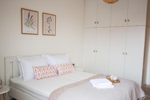 a white bedroom with a bed with white cabinets at La Petite Fleur Guesthouse in Xylokastron