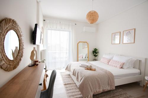 um quarto branco com uma cama e um espelho em La Petite Fleur Guesthouse em Xylokastro