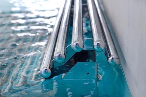 a swimming pool with blue water and metal rails at Vip's Motel Luxury Accommodation & Spa in Lonato del Garda
