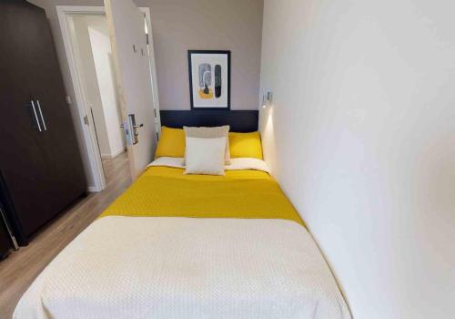 4 Bed, 3 Bath Apartment in City Centre في بورتسماوث: غرفة نوم بسرير كبير عليها شراشف صفراء وبيضاء
