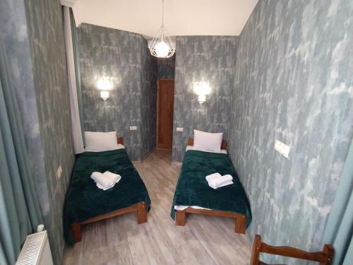 two beds in a small room with green sheets at Gogichas tower in Borjomi