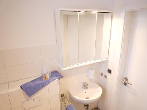 W białej łazience znajduje się umywalka i lustro. w obiekcie Strandnah 12 Pers Gruppenhaus K8 w mieście Zierow