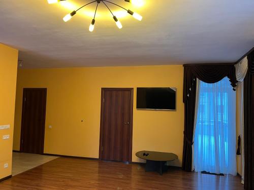 an empty living room with yellow walls and a chandelier at Cat Garden Elegant Apartments Riga in Rīga