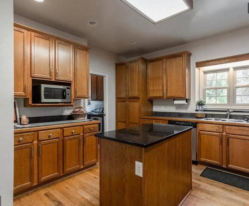 a kitchen with wooden cabinets and a black counter top at Cozy Cabin w/ Indoor Fireplace & Tranquil views in Luray