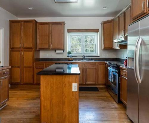 a kitchen with wooden cabinets and a stainless steel refrigerator at Cozy Cabin w/ Indoor Fireplace & Tranquil views in Luray