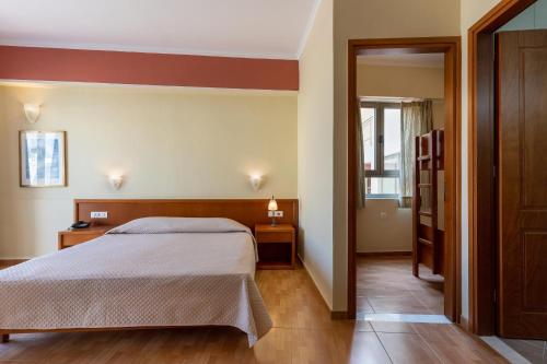a bedroom with a bed and a door to a hallway at Hydramis Palace Beach Resort in Georgioupolis