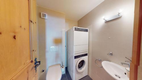 a bathroom with a toilet and a sink and a washing machine at Tschuetta in Celerina
