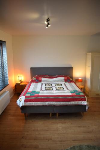 a bedroom with a bed with a quilt on it at B&B Houten Huis in Nazareth