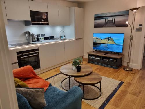 a living room with a couch and a table and a tv at Ritual Stays stylish 1-Bed Flat in the Heart of St Albans City Centre with Working Space and Super Fast WiFi in Saint Albans