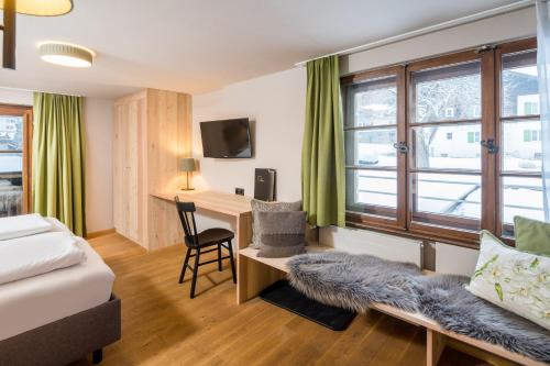 a bedroom with a desk and a bed and a window at Hotel Sonne in Brand