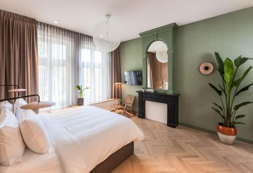 a bedroom with a large white bed and a fireplace at Hotel Arena in Amsterdam