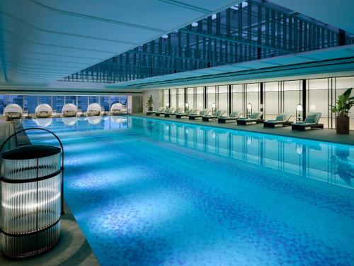 - une grande piscine avec des chaises dans un bâtiment dans l'établissement Jing An Shangri-La, Shanghai, à Shanghai