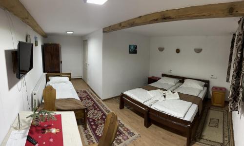 um quarto com 2 camas, uma mesa e uma televisão em Casa Maria em Vişeu de Sus