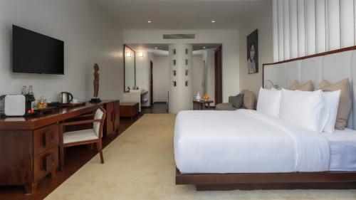 a bedroom with a large white bed and a desk at Shintana Saya La Maison in Siem Reap