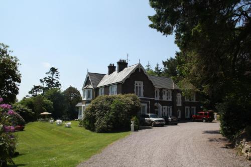 a large black house with cars parked in the driveway at Maranatha Country House in Blarney