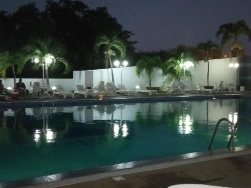 una piscina por la noche con palmeras y luces en Airport BleuSuite Apartment, en Catia La Mar