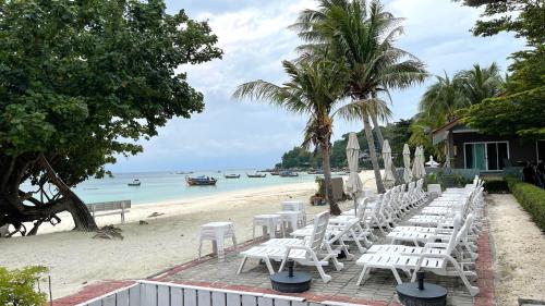 a row of white chairs on a beach at Bella Vista Beach Resort Koh Lipe in Ko Lipe